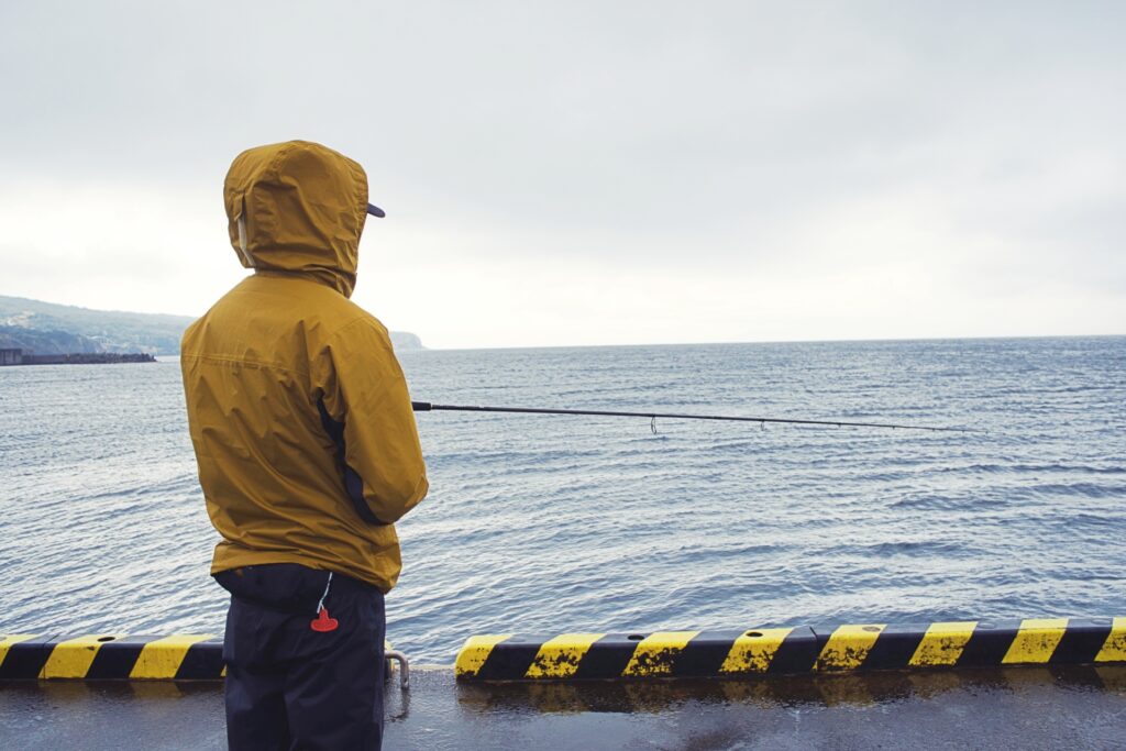 釣り用レインウェアを着て雨の中で釣り